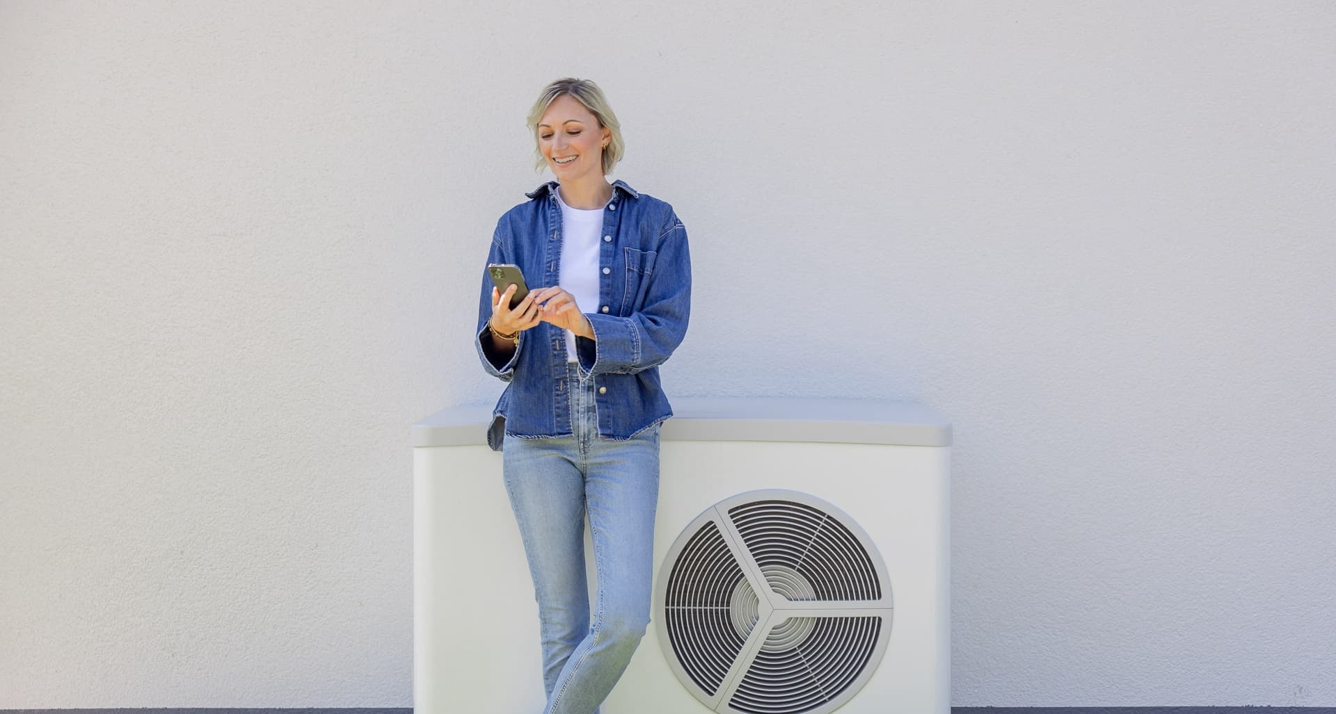 Kvinde ved varmepumpe kontrollerer sin app